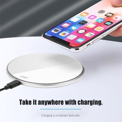 Carregador sem fios redondo prateado com smartphone e texto em inglês