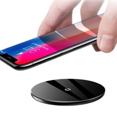 Smartphone sendo colocado sobre carregador sem fios redondo preto