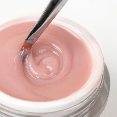 Frasco com gel ou creme rosa claro e espátula metálica