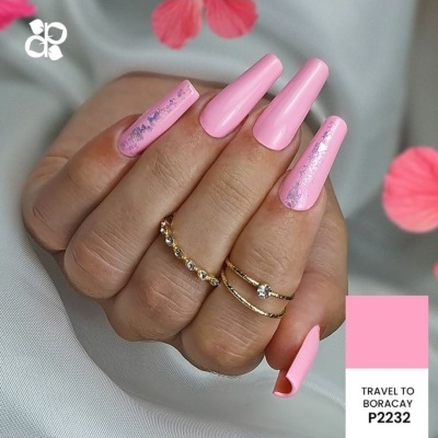 unhas artificiais rosa com detalhes metálicos e anéis dourados na mão