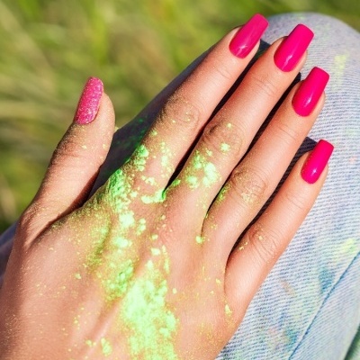Mão com unhas rosa vibrante e pó verde fluorescente, texto 378 DELULU e DOPAMINA GEL POLISH.
