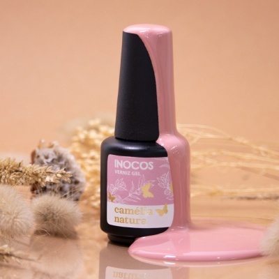 Frasco preto de verniz gel Inocos rosa com verniz derramado e flores secas ao fundo