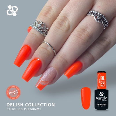 Mão feminina com unhas pintadas de verniz gel néon laranja e rosa brilhante, anéis prateados e frasco de verniz P2180 Delish Gummy da Purple.