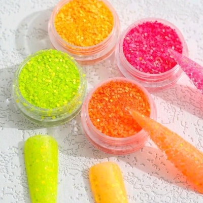 Quatro potes de glitter colorido com amostras de unhas postiças e pincéis aplicadores