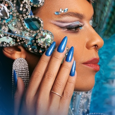 Pessoa com maquiagem e acessórios faciais azuis e brilhantes, unhas azuis metálicas longas, acessórios prateados e texto '365 Divertida'.