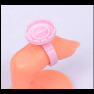 Anel plástico rosa com desenho de cápsula num dedo de manequim laranja