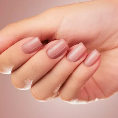 Mão feminina com unhas rosa nude brilhantes e formato quadrado