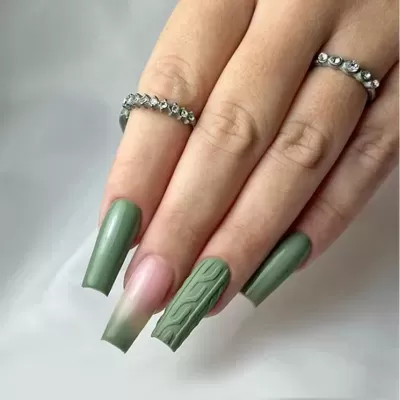 Mão com unhas verdes decoradas e dois anéis prateados com pedras