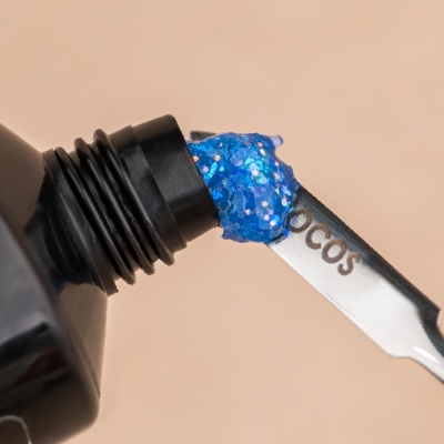 Verniz de unhas azul com glitter em frasco preto aberto com espátula