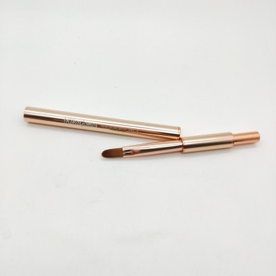 Pincel de maquilhagem dourado com tampa removida sobre fundo branco