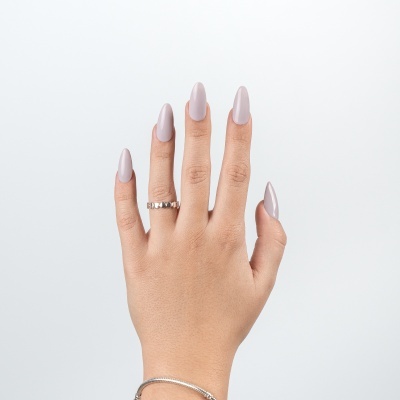 Mão feminina com unhas cinza claro e anel prateado em fundo branco