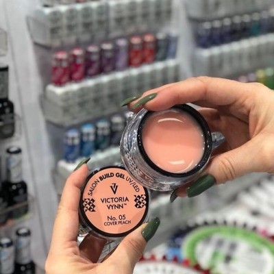 Frasco pequeno de gel de construção para unhas Victoria Vynn cor pêssego em mãos femininas