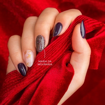 Mão com unhas decoradas segurando tecido vermelho