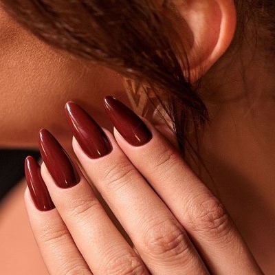 Unhas castanhas escuras brilhantes compridas em mão feminina