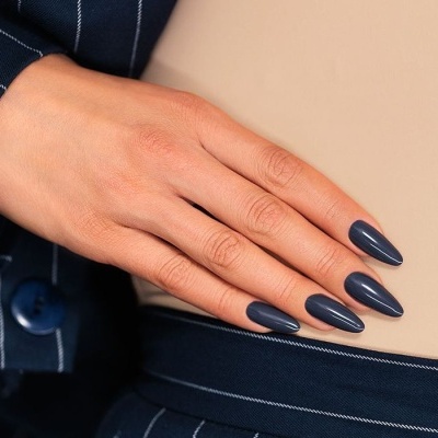 Mão com unhas azul escuro e roupa azul riscada