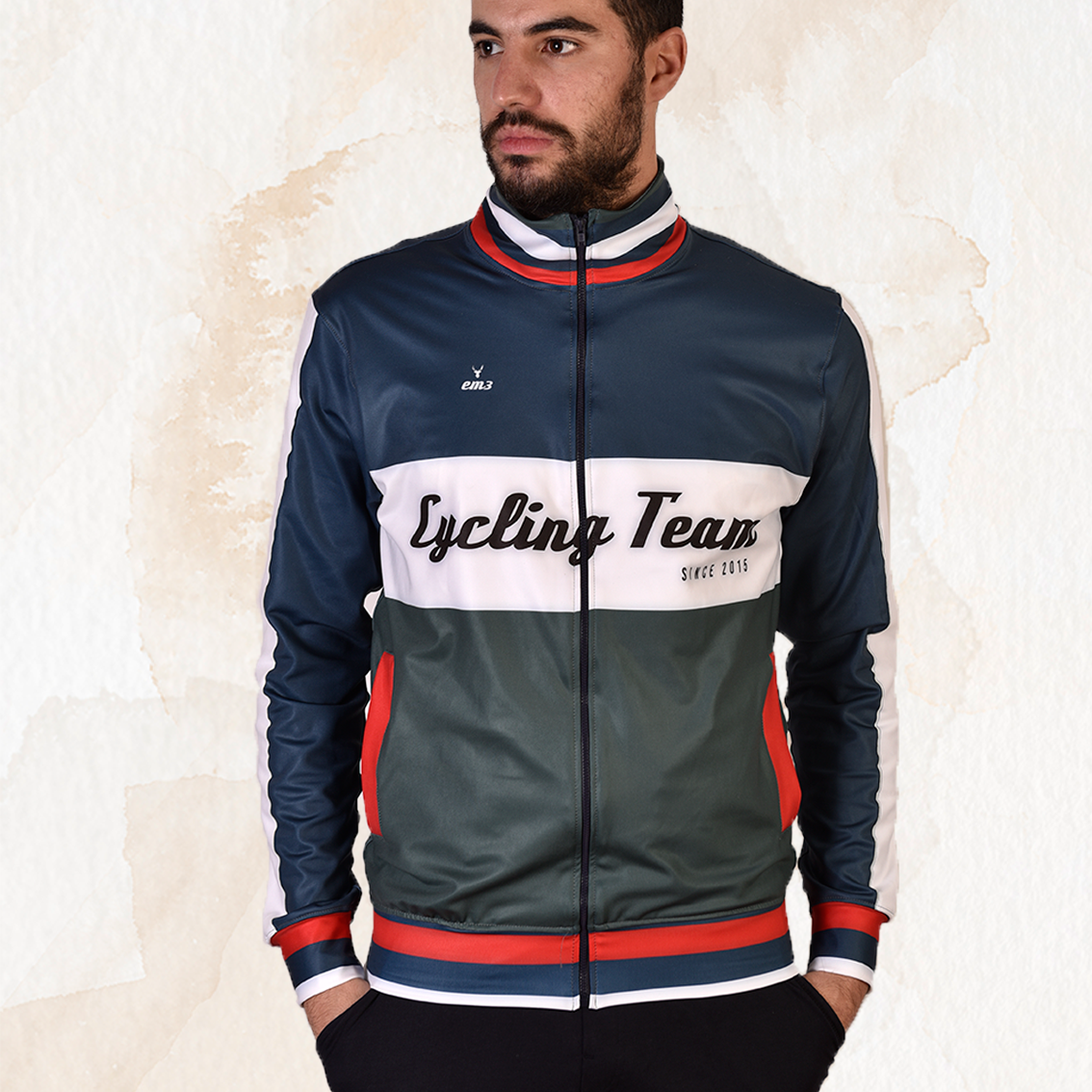 Homem vestido com casaco de ciclismo azul escuro, branco e verde com detalhes vermelhos e texto 'Cycling Team'