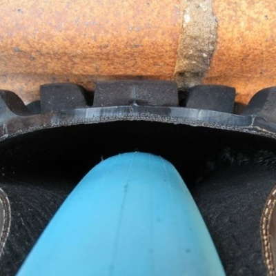 Ferramenta de jardinagem com cabo azul e ponta preta encostada em tijolo