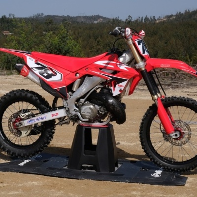 Motocross vermelha com número 23 em terreno de terra