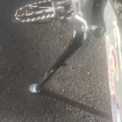 Descanso lateral e pedal metálico de mota sobre pavimento asfaltado