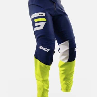 Calças de motocross azul escuro, amarelo e branco com texto 'SHOT'