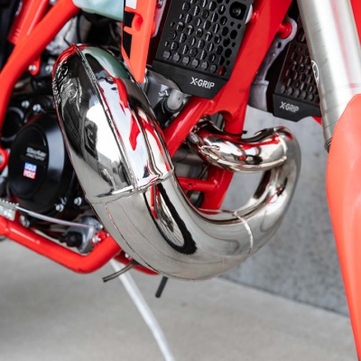 Tubo de escape cromado em moto vermelha com componentes pretos e laranja