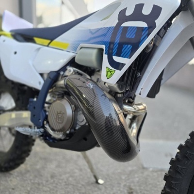 Motocross branco com detalhes azuis e amarelos, escape em carbono, montada em exterior