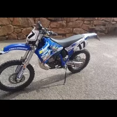 Mota de motocross azul e branca com o número 17 e stickers de várias marcas