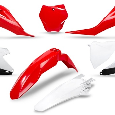 Peças de plástico para moto em vermelho, branco e preto, dispostas sobre fundo branco