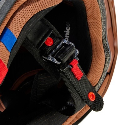 Interior de capacete com acolchoamento castanho e fivela preta com detalhes vermelhos