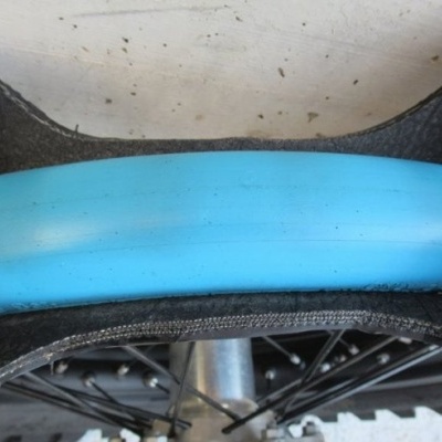 Roda de bicicleta com pneu azul claro, raiaos e guarda-lamas preto