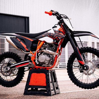 Motocross preta e laranja com pneus de cravos em suporte