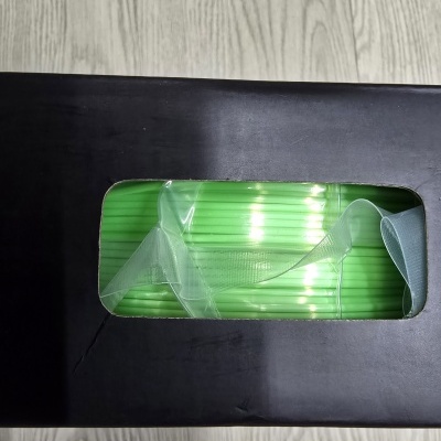 Pacote preto com rolo verde brilhante visível através de janela transparente.