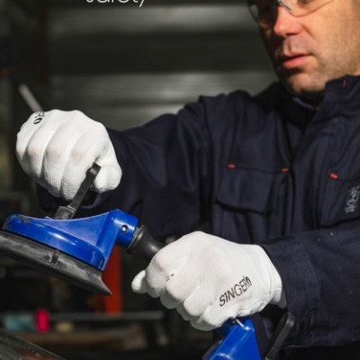 Trabalhador com luvas SINGER segurando ferramentas de sucção azuis.