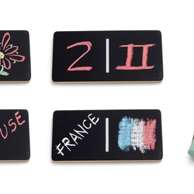 Pequenos quadros negros com desenhos coloridos a giz e uma caixa de giz colorido.