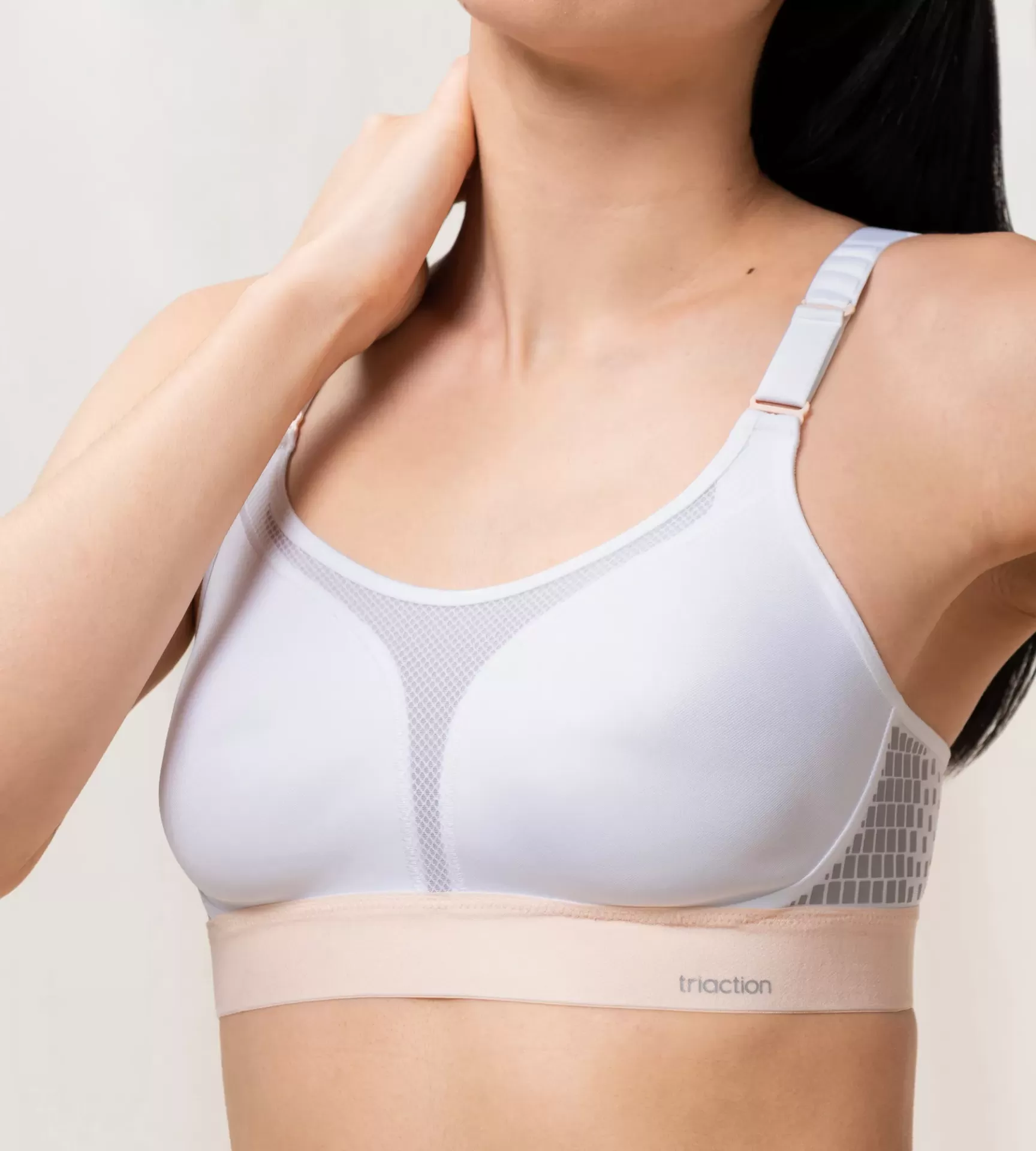 Soutien desportivo branco e bege com tirantes ajustáveis e detalhe em malha.