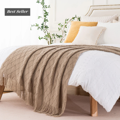 Cama com roupa de cama branca e manta castanha em quarto decorado