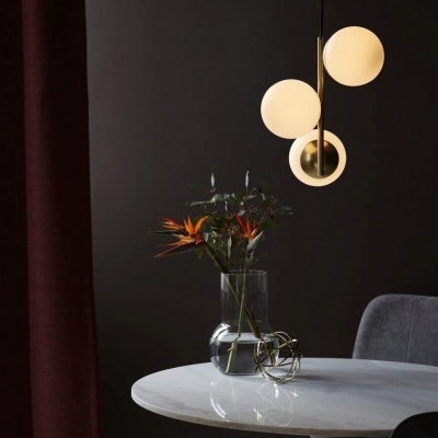 Mesa branca redonda com vaso de flores e candeeiro suspenso de esferas opacas e metal dourado