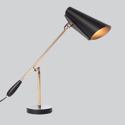 Candeeiro de secretária preto e dourado sobre fundo cinzento