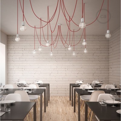 Restaurante com lâmpadas pendentes de fios vermelhos, mesas escuras e cadeiras brancas