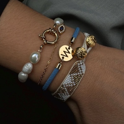 Quatro pulseiras femininas com pérolas, correntes douradas, fio azul e pulseira têxtil branca com contas douradas