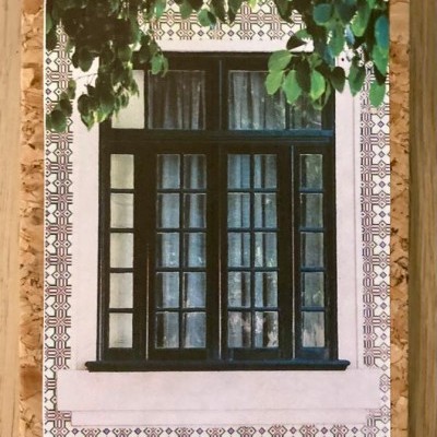 Bloco de notas com capa de cortiça e fotografia de janela preta com padrões decorativos e folhas verdes