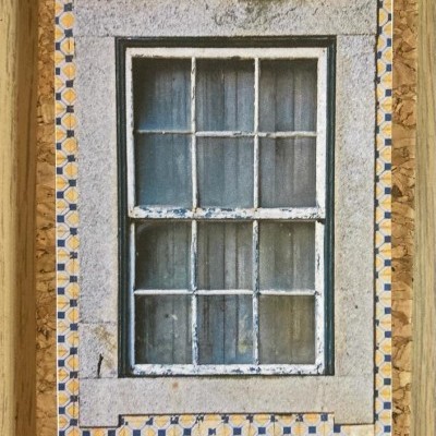 Capa de caderno com fotografia de janela antiga e moldura de azulejos amarelos e azuis em cortiça
