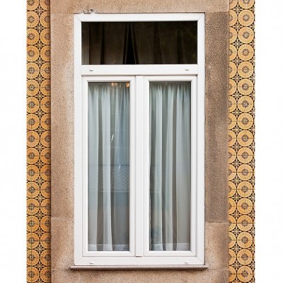 Janela branca com cortinas em parede de azulejos decorativos amarelos e castanhos