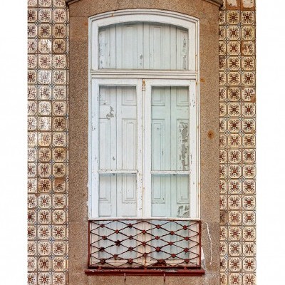 Janela antiga branca em parede de azulejos com moldura de pedra e grade metálica