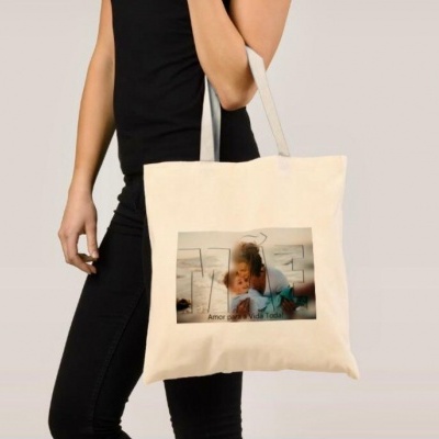 Mala de tecido bege com foto e texto impresso a ser usada ao ombro