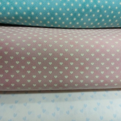 Três rolos de tecido com padrão de corações em azul, rosa claro e branco