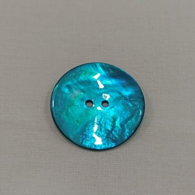 Botão azul redondo brilhante sobre tecido bege