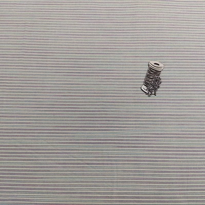 Rolo de fio preto e branco sobre superfície com linhas horizontais cinza e branco