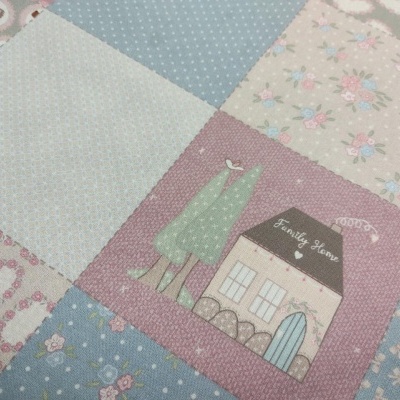 Manta patchwork com padrões florais e casa desenhada em tons suaves