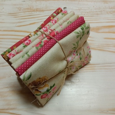 Pedaços de tecido decorados dobrados e amarrados com cordão sobre madeira clara